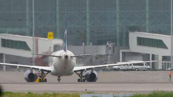 Airplane with an unrecognizable livery is taxiing to the terminal. Airliner is arriving. An airplane following a car. video