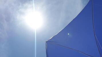 Beach umbrella and bright summer sun into a blue sky. First-person view of tanning and resting on the beach video