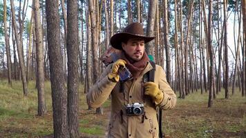 A backpacker with a guitar and a camera walks along a trail in the forest. Travel concept. Slow motion video