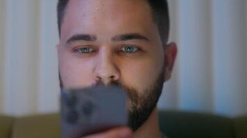 Close up Caucasian man face mobile phone smartphone telephone cellphone gadget online internet using technology insomnia stuck addiction networking guy male connection cyberspace web browser virtual video