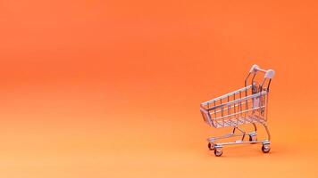 Supermarket concept. An empty supermarket trolley isolated on an orange background. Free space for your text, copy space photo