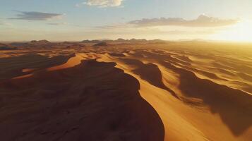 Sprawling desert landscape, captured from above by a drone. Patterns in the sand dunes with sharp shadows during the golden hour, giving a dramatic and expansive view. photo