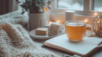 A cozy indoor scene of someone journaling with a cup of tea by their side. The setting is warm and inviting, with soft lighting, comfortable blankets, and personal items like books or plants nearby. photo