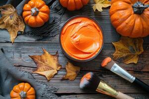 Pumpkin face mask on a wooden table, top view, with pumpkin, brush and autumn leaves. photo