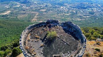 Young man standing with open arms on top of an old ruined building enjoying the view of the valley photo