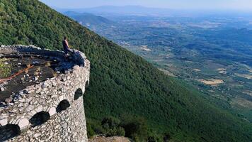 A solitary figure enjoys the breathtaking view from an ancient stone tower perched on a mountain during a clear day in the countryside photo