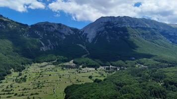 Vast green valley embraced by towering mountains under a vibrant blue sky during mid-afternoon light photo