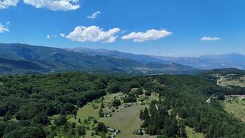 Breathtaking view of lush green valleys and distant mountains under a blue sky with fluffy clouds photo