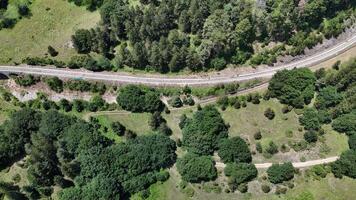 Aerial view of a winding railway nestled among vibrant green forests in the serene countryside during a sunny afternoon photo