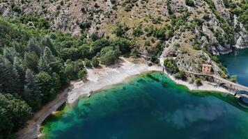 Serene shoreline embraced by lush greenery and rocky cliffs at a tranquil lake during a bright sunny day in early summer photo