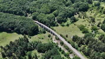 Aerial view of a historic railway viaduct nestled among lush green forests and rolling hills on a sunny afternoon photo