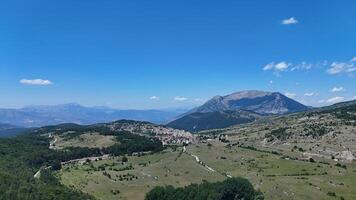 Majestic mountains framing a serene village under a vibrant blue sky in the heart of the countryside during midday photo