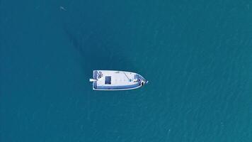 A serene view of a small boat gently drifting on calm turquoise waters in the afternoon sun near a tranquil coastal area photo
