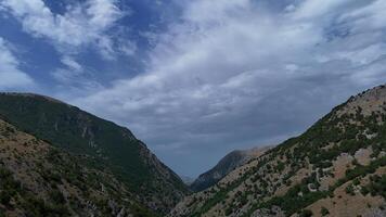 A serene valley nestled between rugged mountains under a dynamic sky at midday invites tranquility and exploration photo