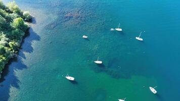 Aerial view of serene lake with sailboats gliding gracefully on calm waters surrounded by lush greenery photo