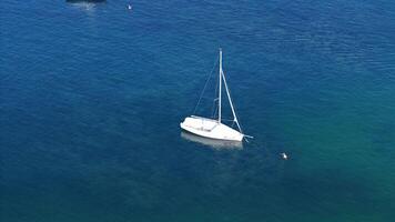 A serene afternoon with a lone sailboat gliding across calm blue waters near a sun-soaked coastline photo