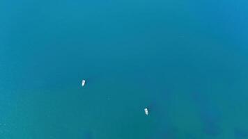 A serene moment on the tranquil blue waters with two boats gliding peacefully under the bright midday sun at a coastal location photo