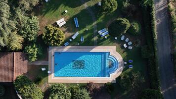 An aerial view of a serene swimming pool nestled in lush greenery, inviting relaxation under the midday sun photo