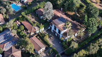 Aerial view of a charming countryside estate with solar panels surrounded by lush greenery and a refreshing pool under bright sunlight photo