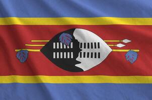 Swaziland flag depicted on folded wavy fabric of old cloth photo