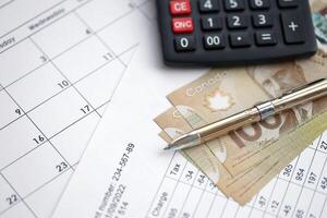 Many calculation results in schedules lies on table with canadian money bills, calculator and pen photo