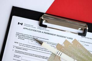 Application for permanent resident card on table with pen and canadian money photo