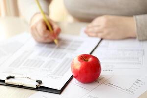 Female student hands testing in exercise and taking fill in exam paper sheet with pencil at school test photo