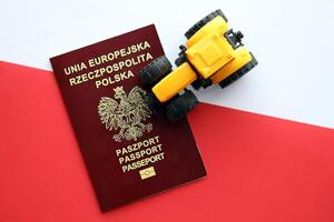 Red polish passport and yellow tractor on smooth red and white flag of Poland photo
