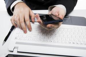 human fingers on the notebook keyboard and smartphone photo
