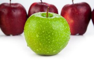 maroon apples lined up in a row and green apple closeup photo