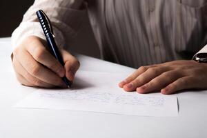 man is writting on a sheet of paper photo