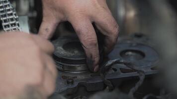 Mechanic installing piston with new rings inside the cylinder. Car engine overhaul video