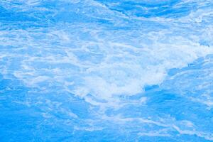 Bluewater waves on the surface ripples blurred. Defocus blurred transparent blue colored clear calm water surface texture with splash and bubbles. Water waves with shining pattern texture background. photo