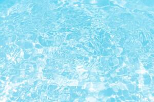 Bluewater waves on the surface ripples blurred. Defocus blurred transparent blue colored clear calm water surface texture with splash and bubbles. Water waves with shining pattern texture background. photo