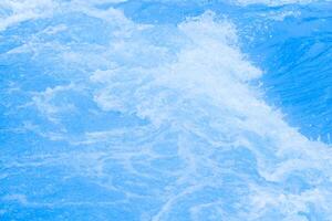 Bluewater waves on the surface ripples blurred. Defocus blurred transparent blue colored clear calm water surface texture with splash and bubbles. Water waves with shining pattern texture background. photo