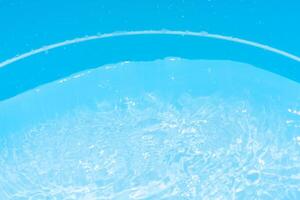 Bluewater waves on the surface ripples blurred. Defocus blurred transparent blue colored clear calm water surface texture with splash and bubbles. Water waves with shining pattern texture background. photo