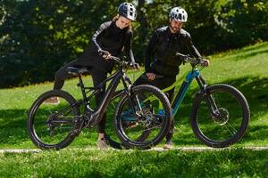 A sweet couple, equipped with bicycles and engrossed in coordinating their journey, checks their GPS mobile and watches while planning scenic routes in the park, seamlessly blending technology and photo