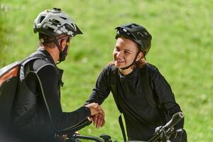 A sweet couple, equipped with bicycles and engrossed in coordinating their journey, checks their GPS mobile and watches while planning scenic routes in the park, seamlessly blending technology and photo