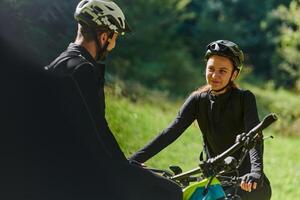 A sweet couple, equipped with bicycles and engrossed in coordinating their journey, checks their GPS mobile and watches while planning scenic routes in the park, seamlessly blending technology and photo
