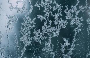 Frozen window glass with melting ice. Wet window background. photo