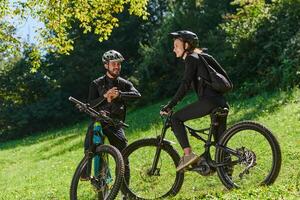 A sweet couple, equipped with bicycles and engrossed in coordinating their journey, checks their GPS mobile and watches while planning scenic routes in the park, seamlessly blending technology and photo
