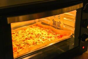 Pizza with tomatoes and meat baking in the oven photo