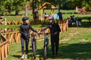 A sweet couple, equipped with bicycles and engrossed in coordinating their journey, checks their GPS mobile and watches while planning scenic routes in the park, seamlessly blending technology and photo