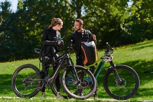 A sweet couple, equipped with bicycles and engrossed in coordinating their journey, checks their GPS mobile and watches while planning scenic routes in the park, seamlessly blending technology and photo