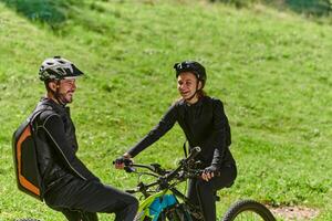 A sweet couple, equipped with bicycles and engrossed in coordinating their journey, checks their GPS mobile and watches while planning scenic routes in the park, seamlessly blending technology and photo