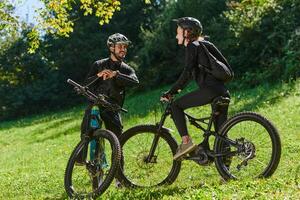 A sweet couple, equipped with bicycles and engrossed in coordinating their journey, checks their GPS mobile and watches while planning scenic routes in the park, seamlessly blending technology and photo