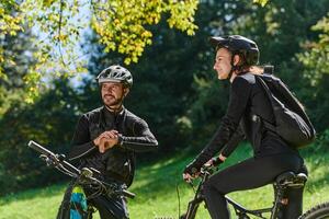 A sweet couple, equipped with bicycles and engrossed in coordinating their journey, checks their GPS mobile and watches while planning scenic routes in the park, seamlessly blending technology and photo