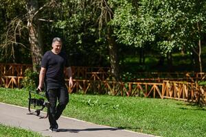 After completing a cinematic venture, a skilled videographer, adorned with camera equipment, leisurely strolls through the park, capturing the essence of post-production satisfaction and creative photo