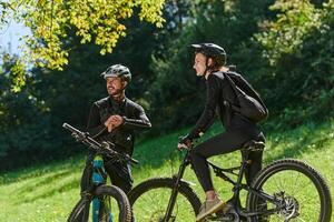 A sweet couple, equipped with bicycles and engrossed in coordinating their journey, checks their GPS mobile and watches while planning scenic routes in the park, seamlessly blending technology and photo