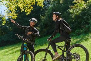 A sweet couple, equipped with bicycles and engrossed in coordinating their journey, checks their GPS mobile and watches while planning scenic routes in the park, seamlessly blending technology and photo